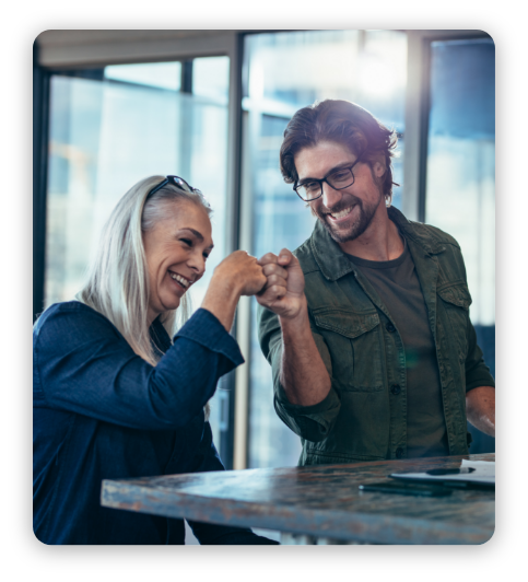 Young businessman and senior businesswoman making a fist bump at office. Business colleagues looking happy and excited after completion of project.