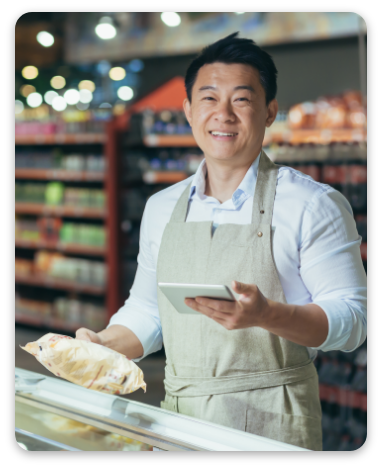 man with tablet checking expiration date of products, seller smiling and looking at camera near refrigerator in supermarket