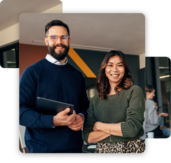 Two happy entrepreneurs smiling at the camera cheerfully. Young businesspeople standing in a boardroom with their colleagues in the background. Diverse entrepreneurs working together as a team.